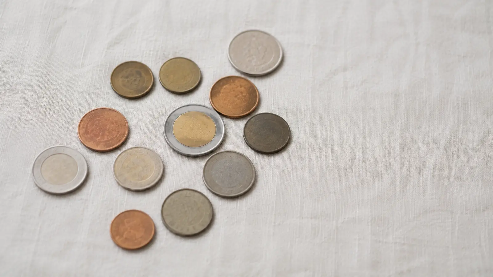 Assorted coins from different countries on a pale surface