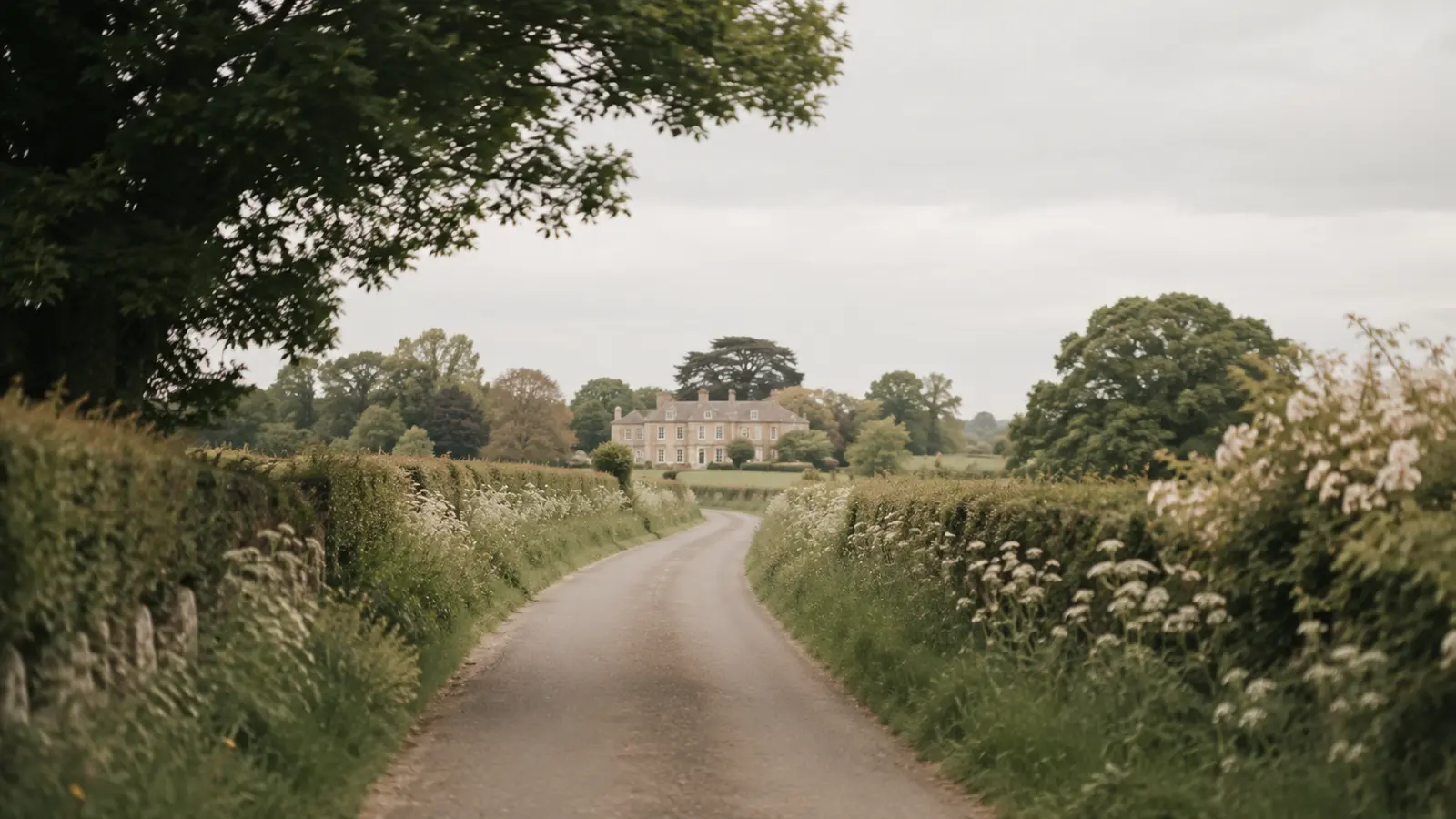 A rural road curving toward a country venue seen through a car window in soft light